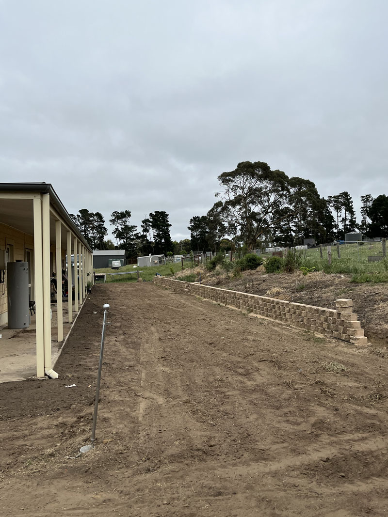 Levelled ground beside a verandah, with a block retaining wall along the boundary