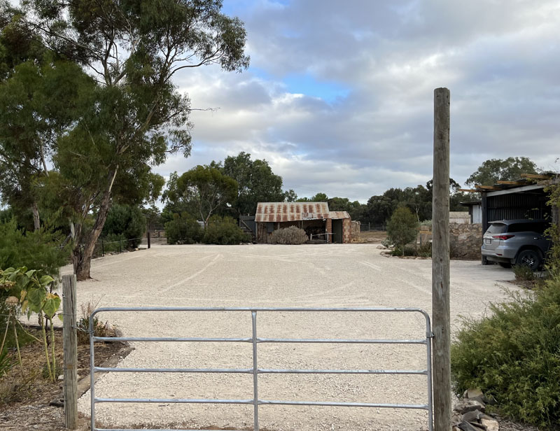 Gravel driveway and parking area behind a metal farm gate