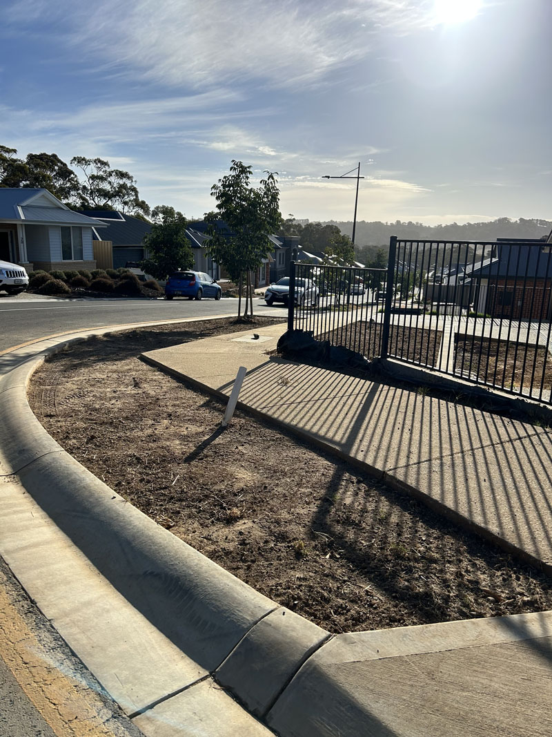 Freshly prepared garden strip along a curved kerb and black fence